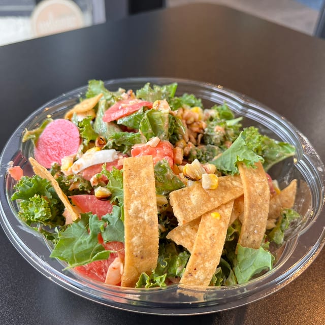 Kale Street Corn Salad, Chipotle Tahini, Kale, Roasted Corn, Plant-based Cheese, Tajin, Cilantro, Pickled Radish, Tomatoes, corn tortilla strips.