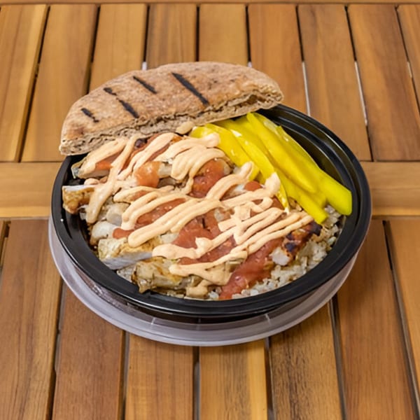 Falafel Taco's chicken shawarma bowl with rice, sauce, and pickled peppers, served with grilled pita bread.