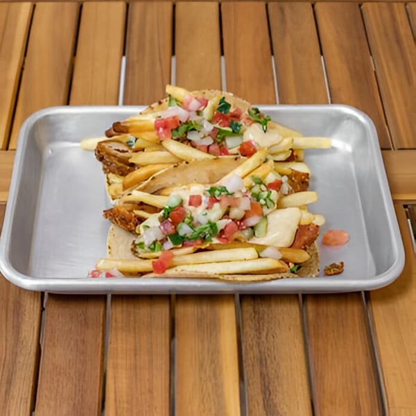 Two Falafel Taco tacos, overflowing with fries, salsa, and sauce, on a metal tray.