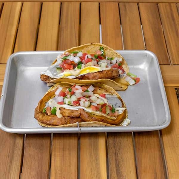Two Falafel Taco breakfast tacos with pico de gallo and fried eggs on a metal tray.